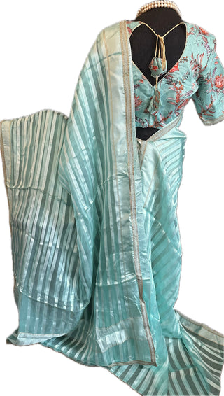 Pastel blue organza saree with gold borders and a stitched blouse