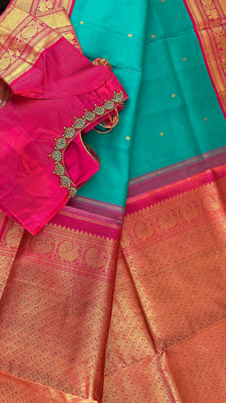 Teal and pink shaded pallu with traditional Kanchipuram motifs woven in silver zari, showcasing handloom artistry.