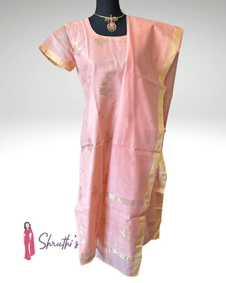 Blush peach organza silk salwar suit with gold zari butta motifs and gold border, displayed on a black mannequin with pink stone choker – traditional Indian outfit for women