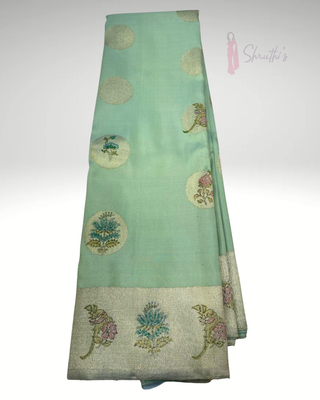 Pure handloom mint green Kanjivaram silk saree with silver zari weaving, elegant floral block prints, and rich traditional border for festive and wedding wear.