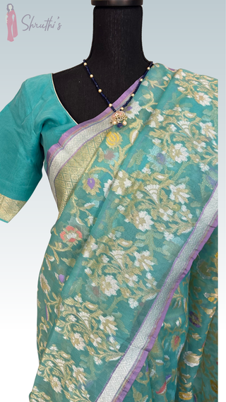 Luxury Banaras handloom pure silk saree in turquoise with shimmering gold zari detailing and stitched blouse, ready to wear and ship worldwide.