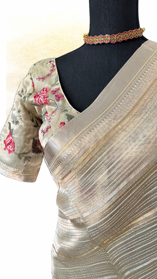 Soft beige-gold tissue silk saree featuring fine weave and embroidered stitched blouse.