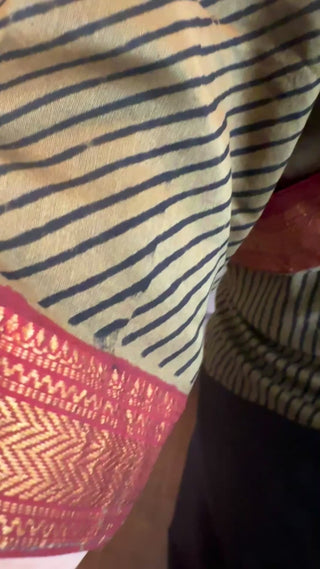 Maheshwari silk cotton saree showing fine black and gold stripes with a rich red zari border, highlighting the smooth texture and handwoven detailing.